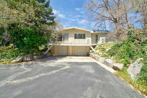 View of front of property featuring asphalt driveway, a garage, a balcony, and brick siding