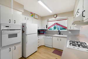 Kitchen with white appliances, light countertops, and white cabinets
