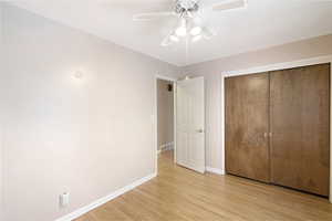 Unfurnished bedroom featuring a closet, light wood-style flooring, and ceiling fan