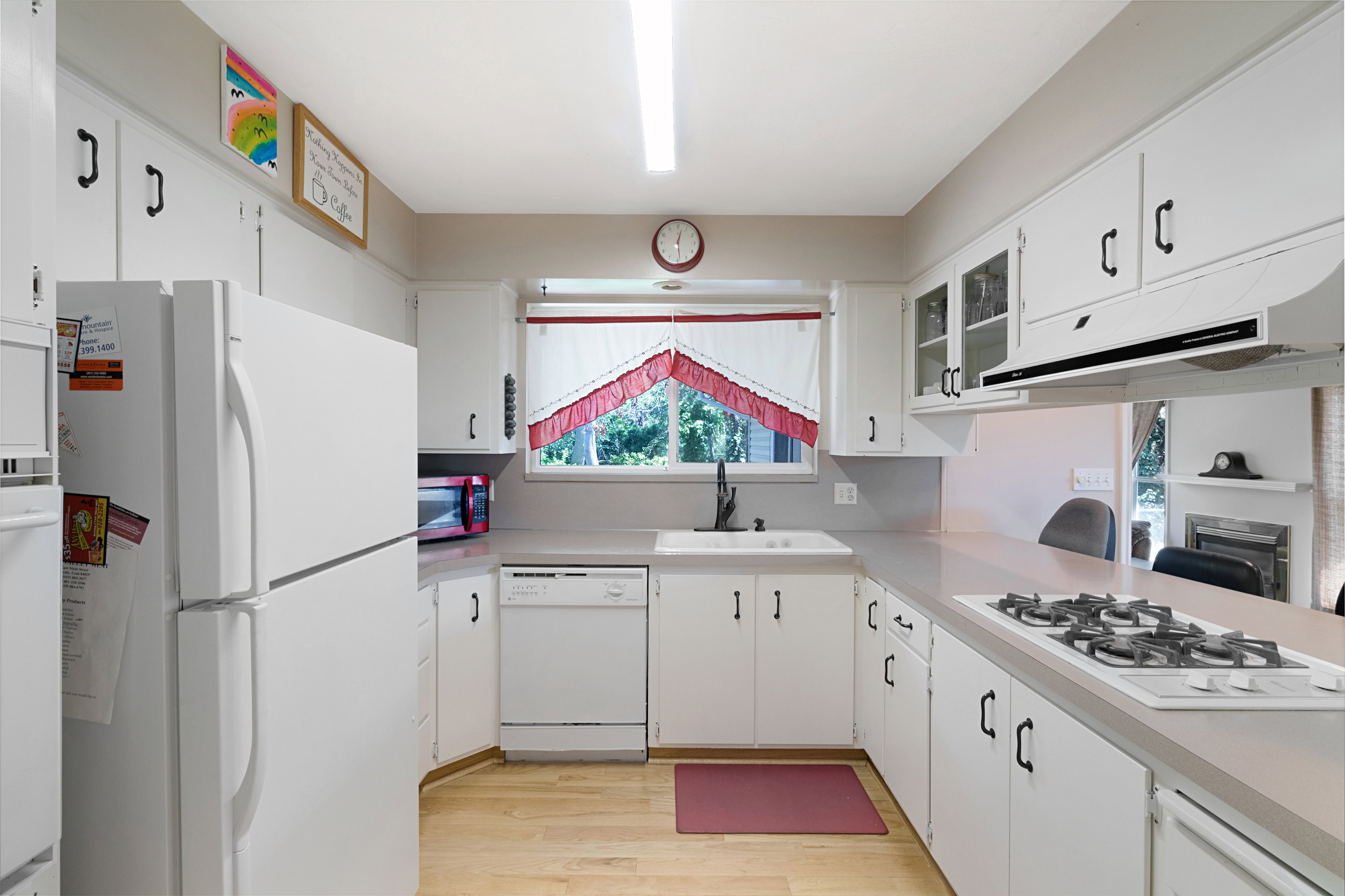 Kitchen with white appliances, light countertops, light wood-type flooring, white cabinetry, and glass fronted cabinets