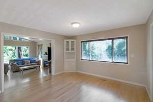 Living area featuring light wood finished floors, a glass covered fireplace, and healthy amount of natural light