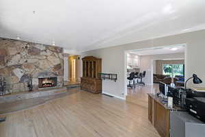 Living area featuring light wood-style flooring and a stone fireplace