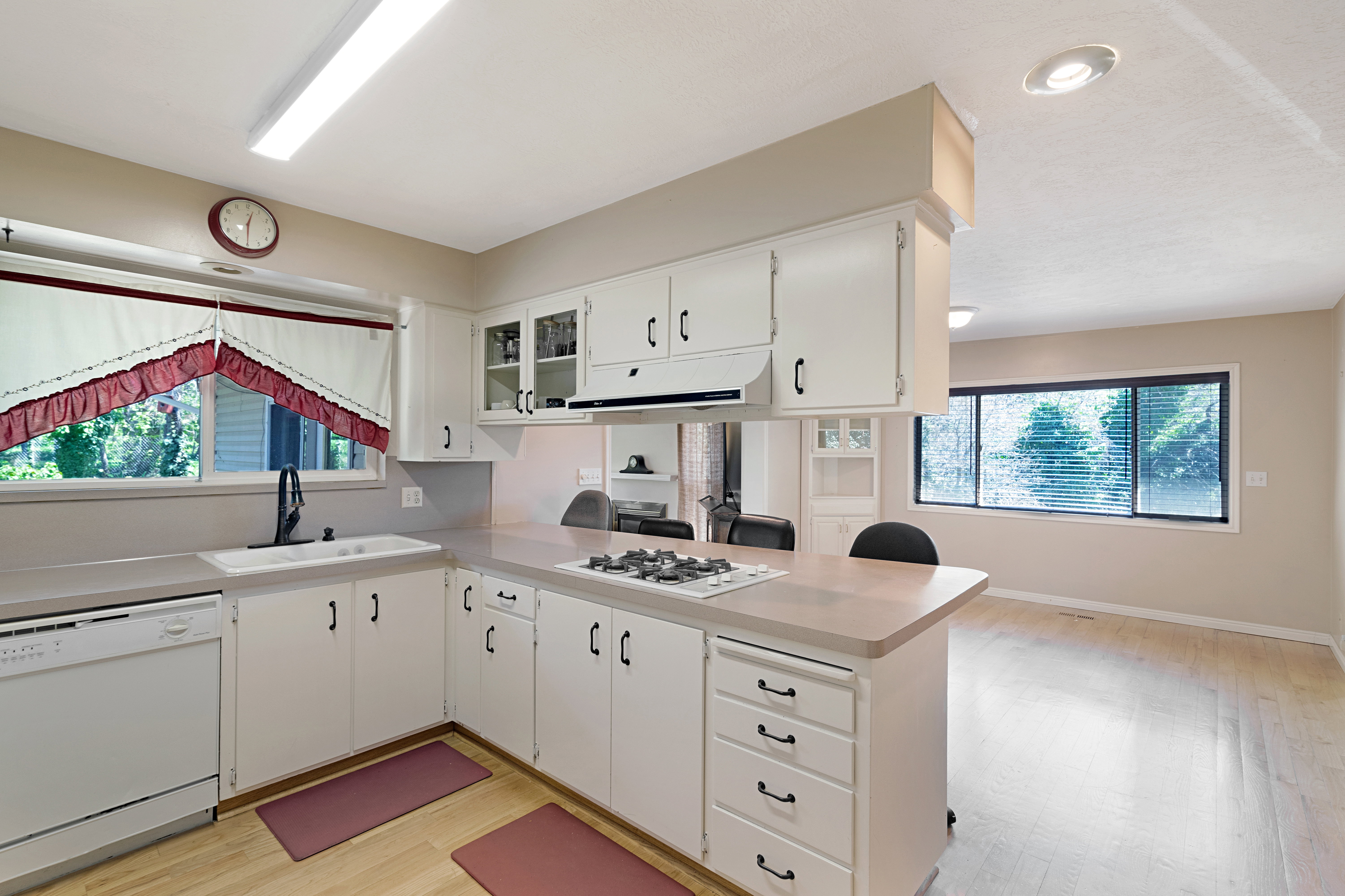 Kitchen featuring a peninsula, white appliances, light countertops, light wood-style flooring, and white cabinets