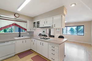 Kitchen featuring a peninsula, white appliances, light countertops, light wood-style flooring, and white cabinets
