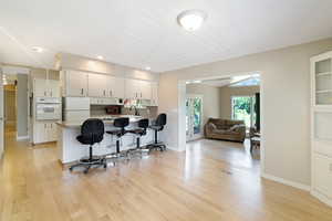 Kitchen featuring a breakfast bar area, white appliances, light countertops, a peninsula, and open floor plan
