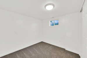 Empty room with dark colored carpet and a textured ceiling