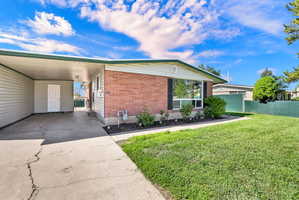 View of front of property with brick siding, concrete driveway, and an attached carport