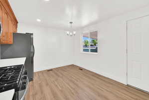 Kitchen with light wood-style flooring, hanging lights, and freestanding refrigerator