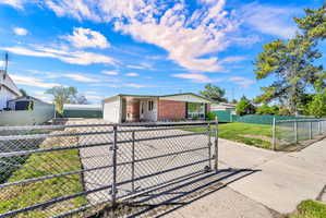 View of front of home with a fenced front yard, a gate, driveway, and brick siding