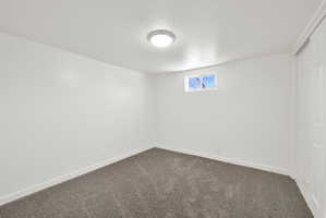 Spare room with a textured ceiling and dark carpet