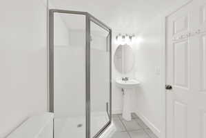 Bathroom with a textured ceiling, a stall shower, and light tile patterned flooring