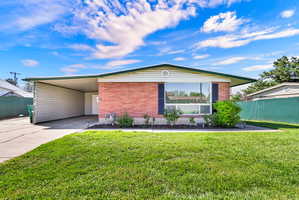 View of front facade with an attached carport, concrete driveway, and brick siding
