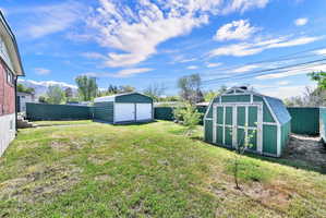 Fenced backyard featuring a storage unit and a garage