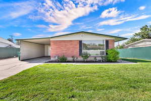 View of front of property featuring a carport, concrete driveway, and brick siding