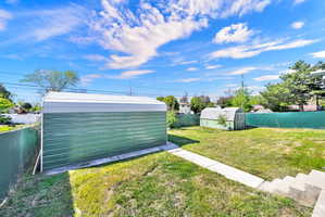 Fenced backyard featuring a shed
