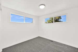 Spare room featuring baseboards and dark carpet