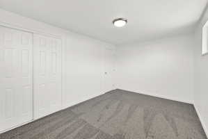 Unfurnished bedroom with dark carpet and a closet