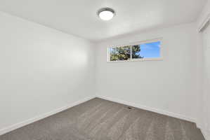 Spare room with baseboards and dark colored carpet