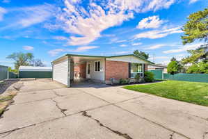 View of front of home featuring driveway, an attached carport, and brick siding