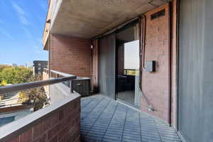 Exterior balcony featuring brick walls, a tiled floor, and a metal railing