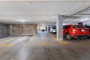 Underground parking garage featuring concrete flooring, fluorescent lighting, and numbered parking stalls