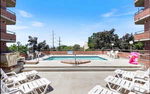 Outdoor pool area featuring a rectangular swimming pool, concrete decking, and red brick exterior architectural elements