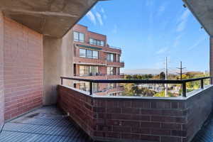 Private balcony featuring brick walls and a black metal railing
