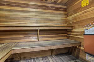 Wood-paneled sauna featuring multi-level wood benches and a built-in heater unit