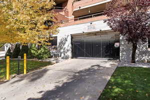 Concrete driveway leading to a gated parking garage entrance within a brick and concrete building