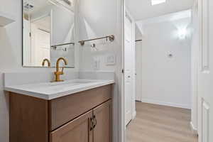 Bathroom vanity with a white countertop and integrated sink, featuring a brass-finish faucet
