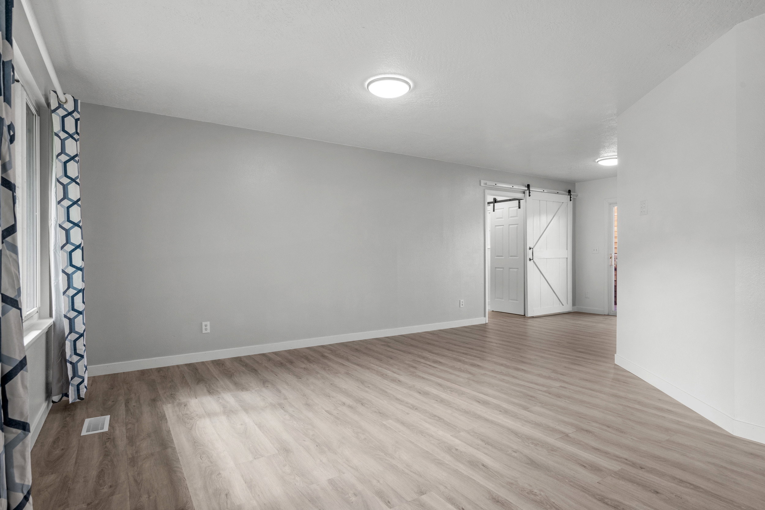Spacious interior featuring wide-plank wood-finish flooring and light gray wall tones