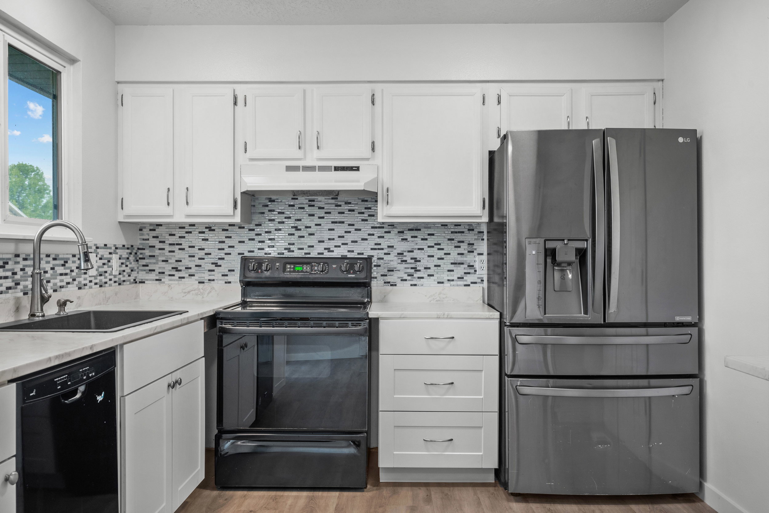 Kitchen featuring white cabinetry, light-toned countertops, and a mosaic tile backsplash