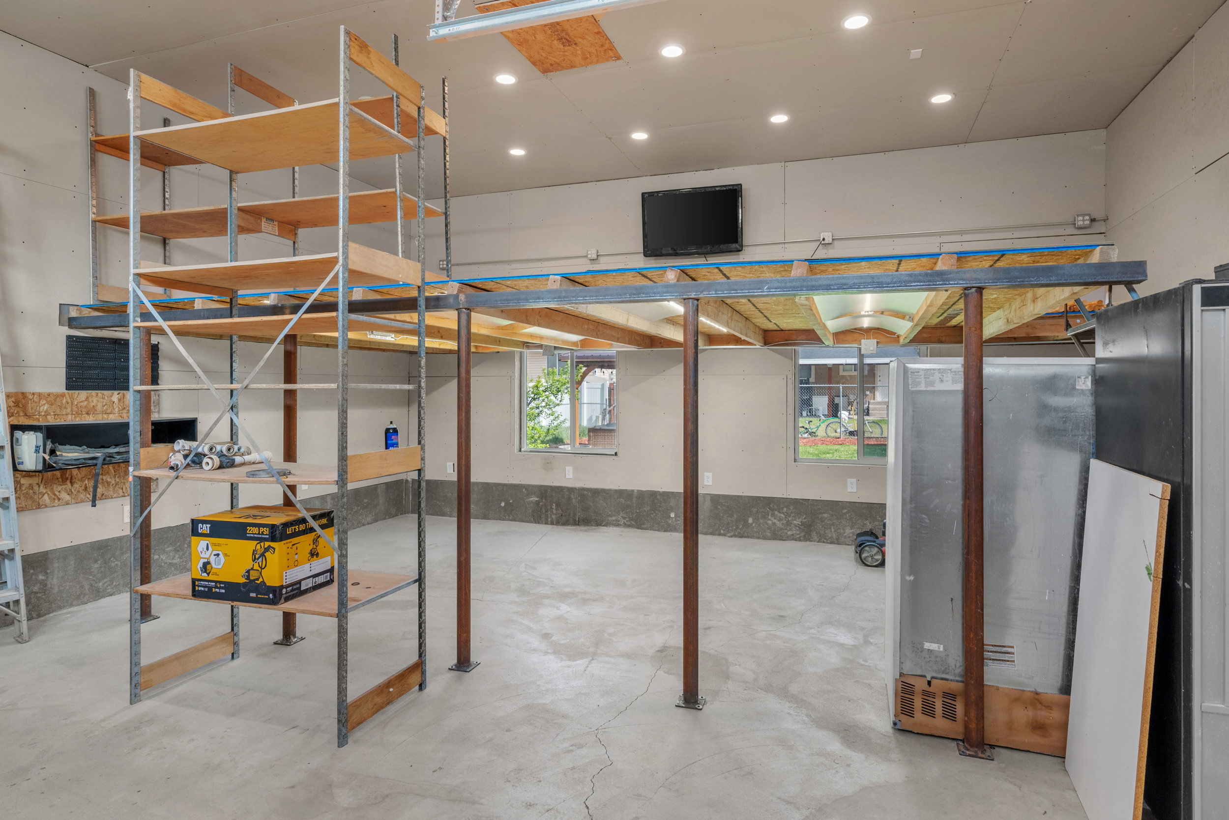 Spacious garage interior featuring high ceilings, concrete flooring, recessed lighting, and multiple windows providing natural light