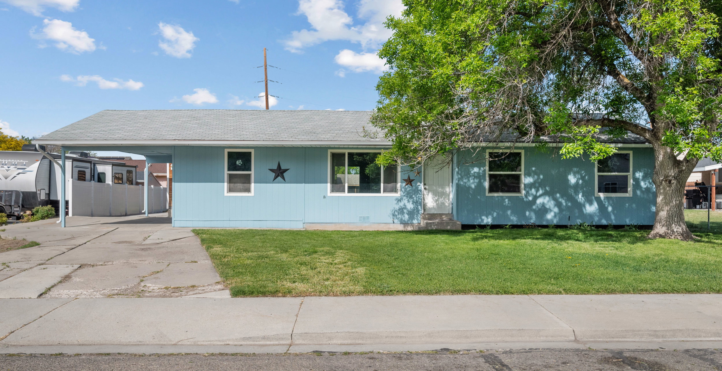 Light blue exterior with white trim and a covered carport
