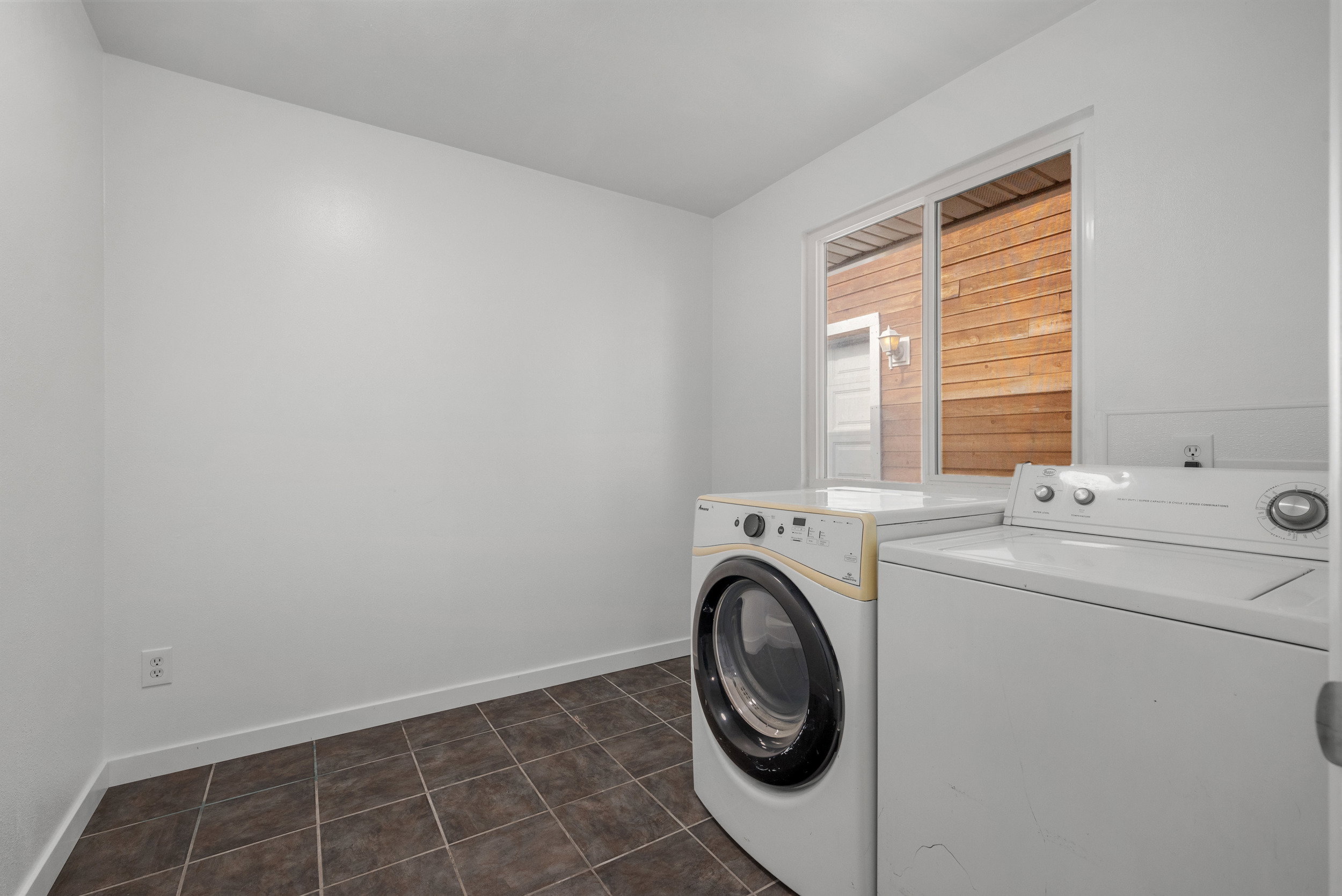 Utility area with tiled flooring, white walls, and a window providing natural light