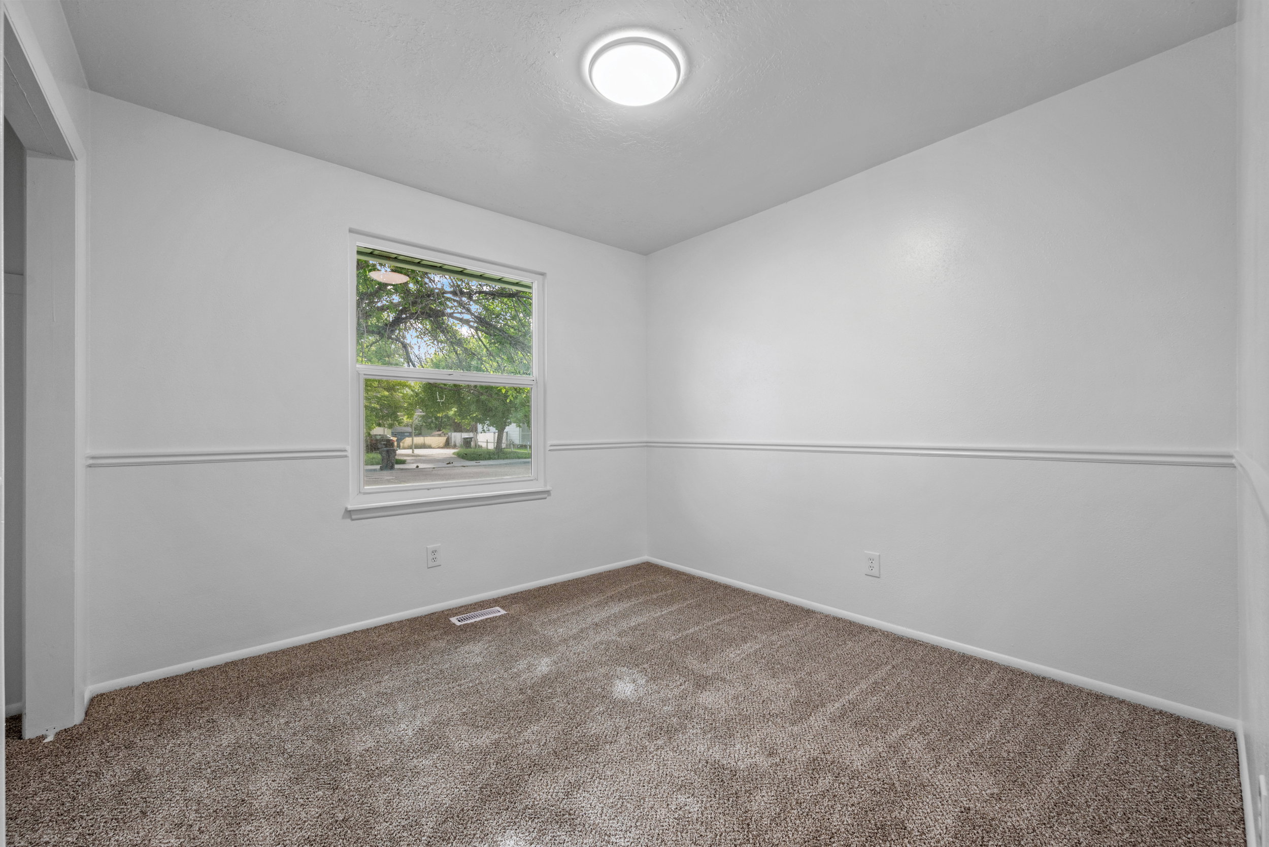 Bright room featuring neutral paint, a single window, and textured carpet flooring