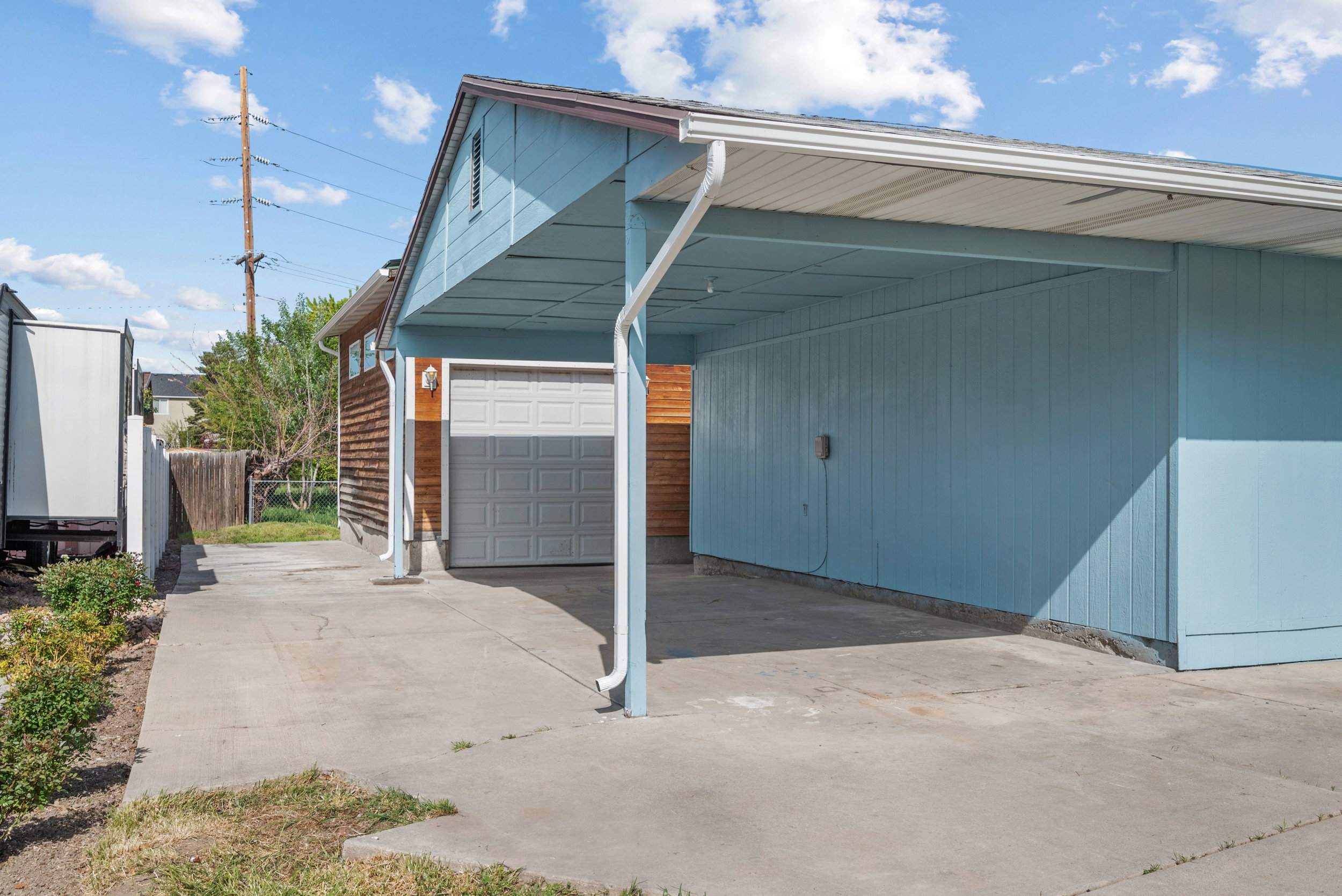 Attached carport and garage with a concrete driveway and light blue siding