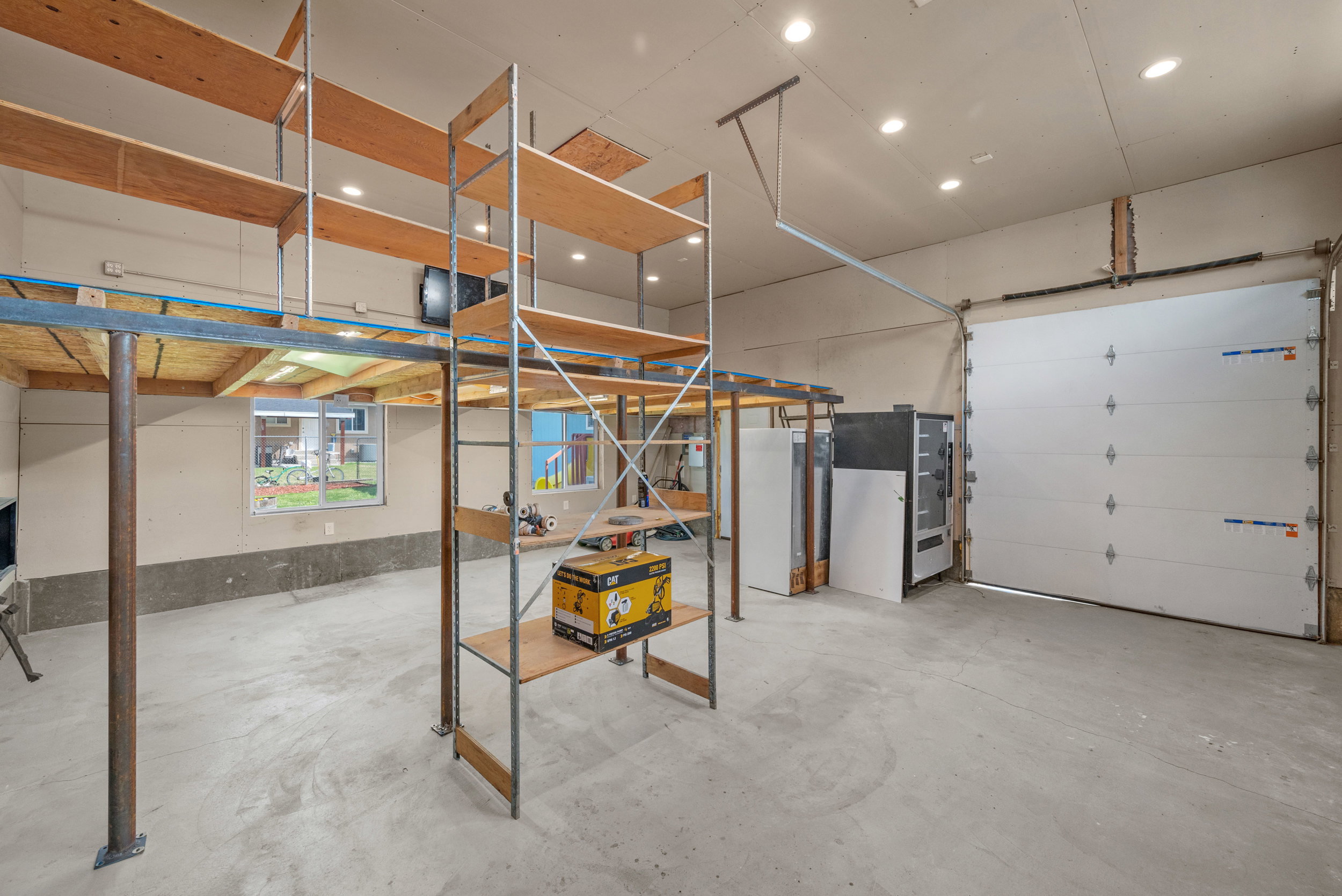 Spacious garage offering significant storage solutions with built-in shelving and an elevated platform