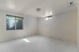 Spacious room featuring white painted walls and floor, multiple windows providing natural light, and a ceiling-mounted light fixture