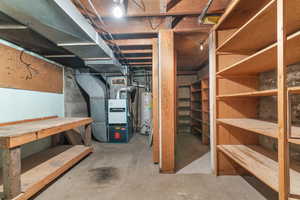 Basement area featuring a concrete floor, exposed ceiling joists, and a workbench