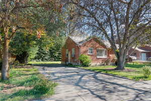 Brick exterior residence with a paved driveway and mature trees