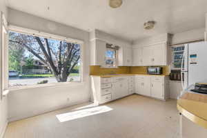 Kitchen featuring a large picture window, white cabinetry, yellow countertops, and a built-in sink