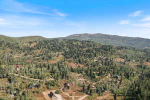 Expansive mountain landscape featuring varied tree cover and multiple scattered properties