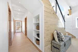 Hallway featuring built-in shelving, recessed ceiling lighting, and light wood-finish flooring