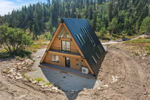 A-frame architectural style with wood panel siding, a black metal roof, a second-story balcony with metal railing, and multiple skylights