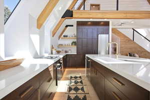Kitchen featuring dark wood-finish cabinetry, white countertops, integrated cooktop, and a built-in oven