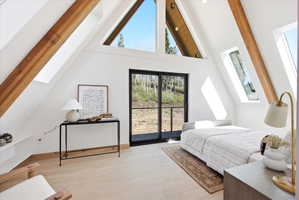Vaulted ceilings featuring exposed wood beams, expansive windows, and a sliding glass door providing outdoor access