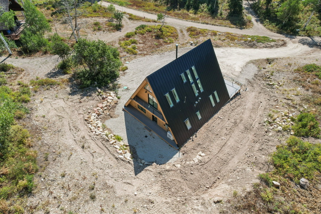 Modern A-frame residence featuring a black corrugated metal roof and siding