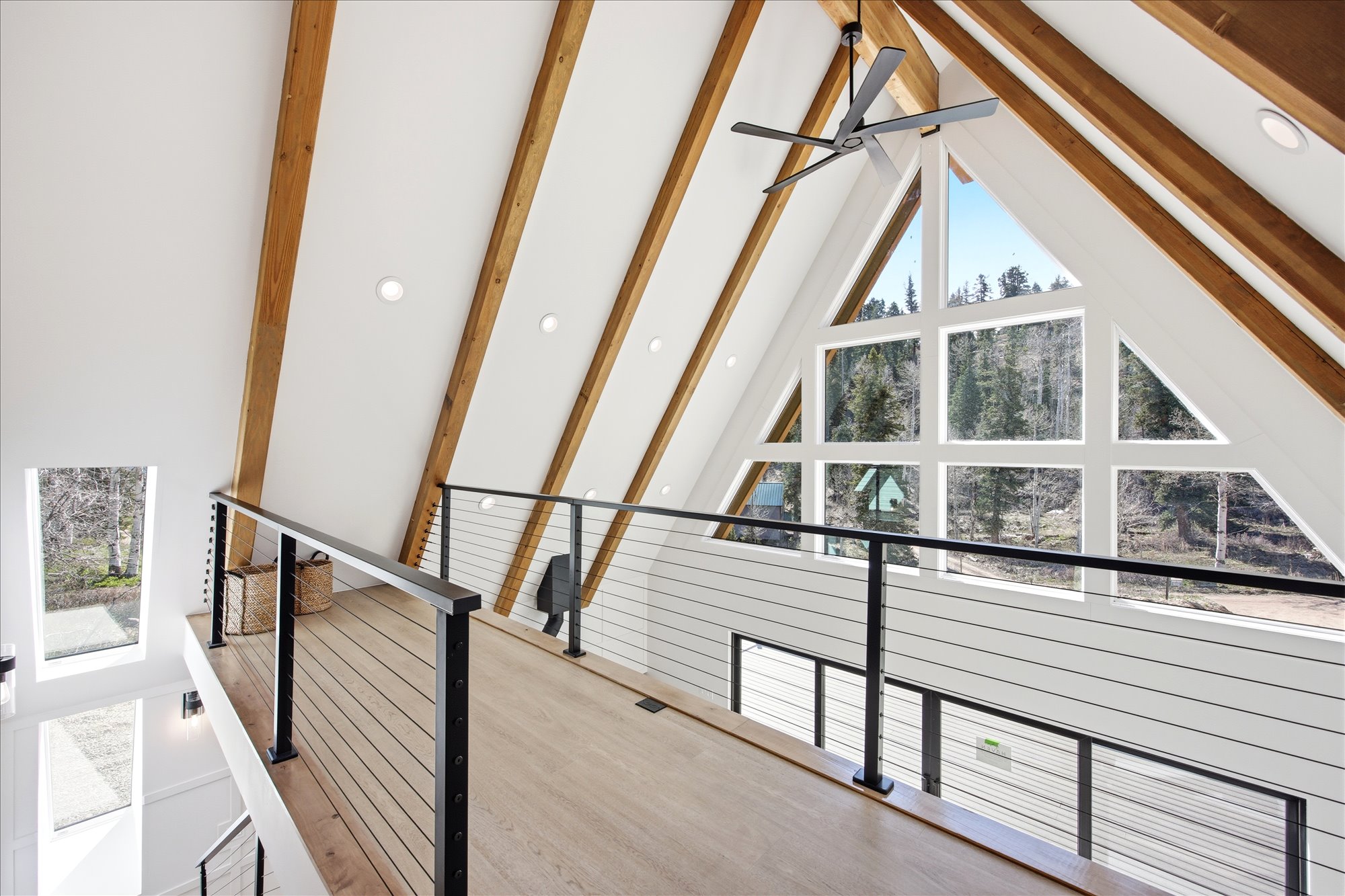 Overlook balcony featuring a cable railing system, wood-finish flooring, and exposed timber ceiling beams