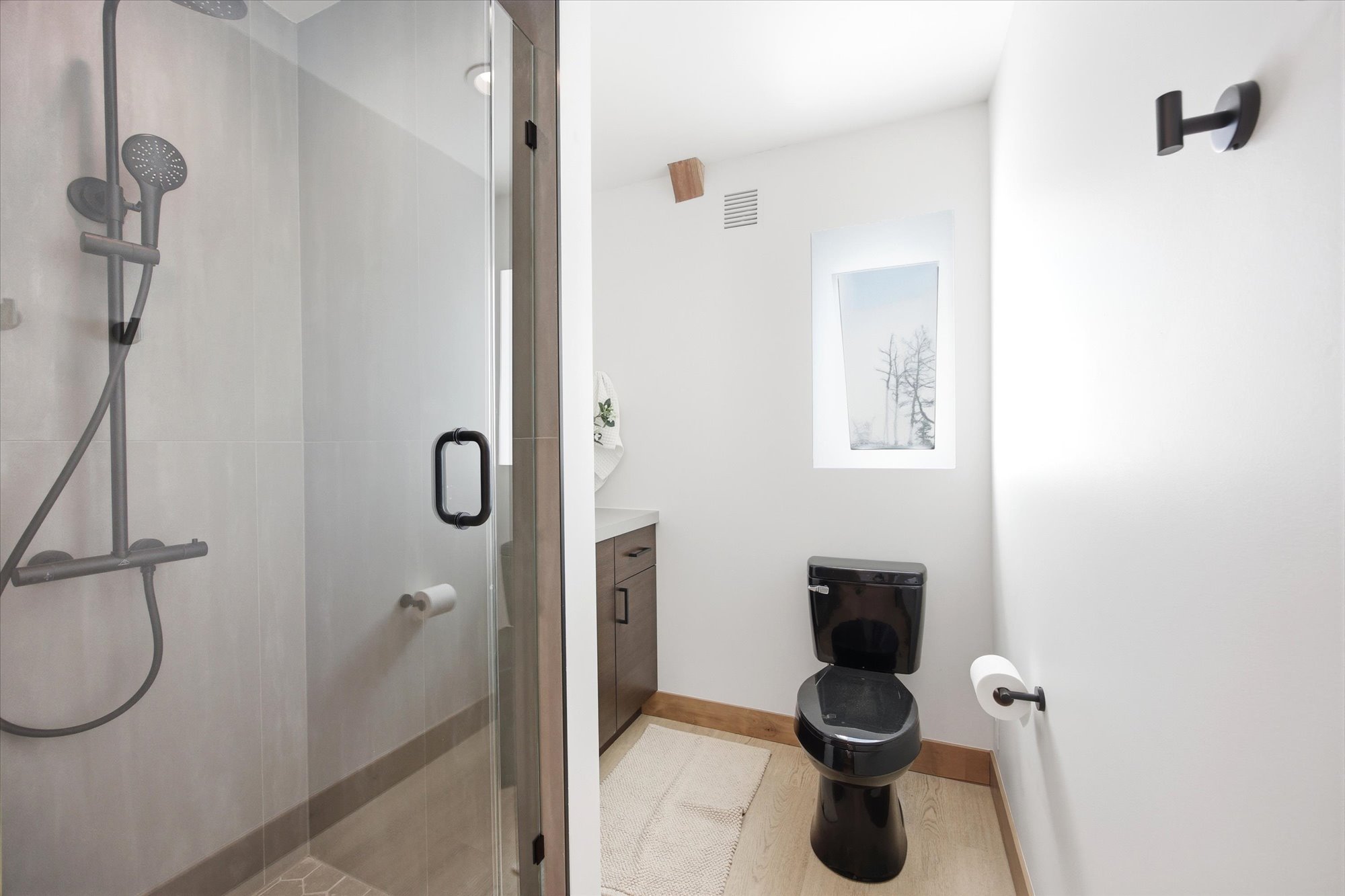 Walk-in shower with clear glass enclosure and matte black fixtures